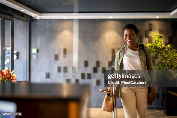 jeune femme confiante arrivant à la réception de l’hôtel - happy hotel guests photos et images de collection