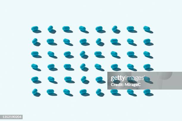 neatly arranged blue capsules - blue capsule stock pictures, royalty-free photos & images