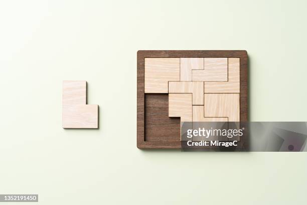 wooden puzzle about to be finished with the final piece - puzzel stockfoto's en -beelden