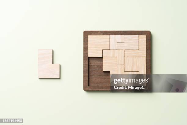 wooden puzzle about to be finished with the final piece - inserting imagens e fotografias de stock