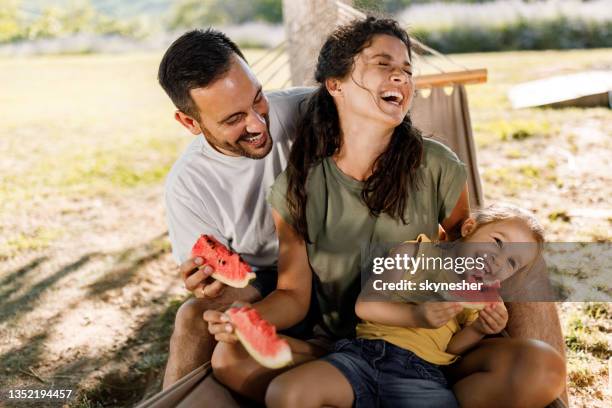 cheerful family eating watermelon in hammock at the backyard. - family backyard stockfoto's en -beelden