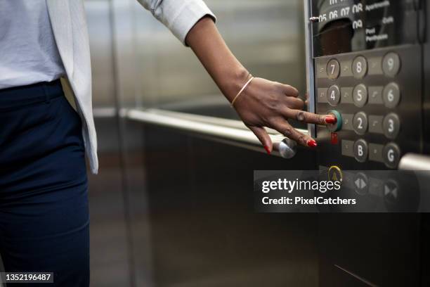 african businesswoman pressing ground floor in elevator - lift stockfoto's en -beelden