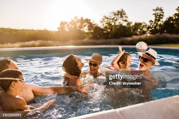 famille élargie ludique s’amusant dans la piscine. - swimming pool photos et images de collection
