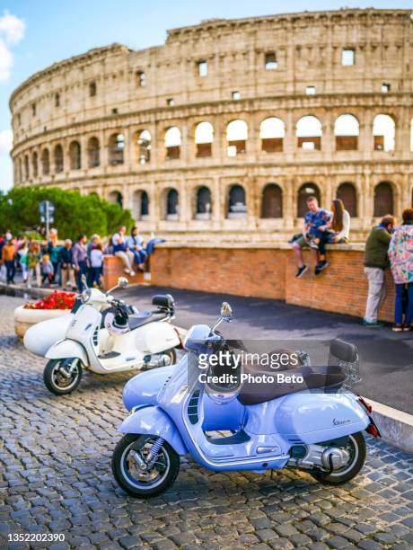 two lovely and characteristic vespa scooters parked near the coliseum in the heart of rome - vespa scooter stockfoto's en -beelden