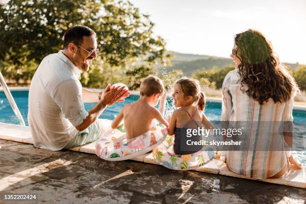 famille heureuse parlant au bord de la piscine en été. - piscine photos et images de collection