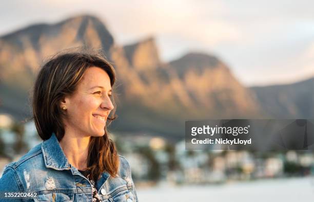 smiling young woman looking out at the ocean in the late afternoon - inlet stock pictures, royalty-free photos & images