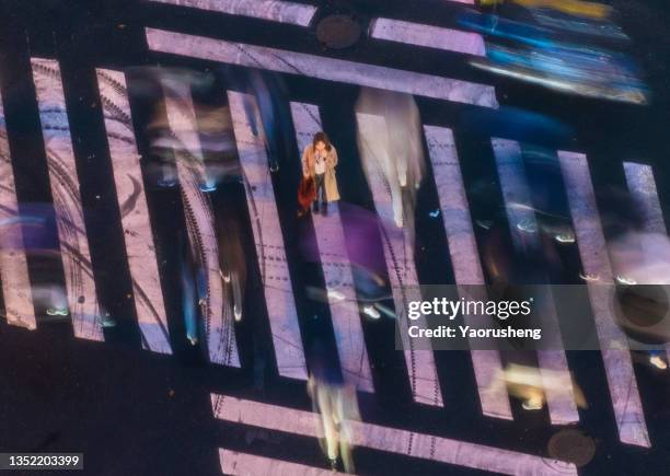 one asian woman holding the red umbrella amidst crowd on the cross road - standing out from the crowd stockfoto's en -beelden