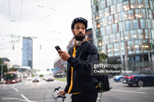 young man commuter with bicycle and smartphone crossing the road in city, sustainable lifestyle. - crossing stock pictures, royalty-free photos & images