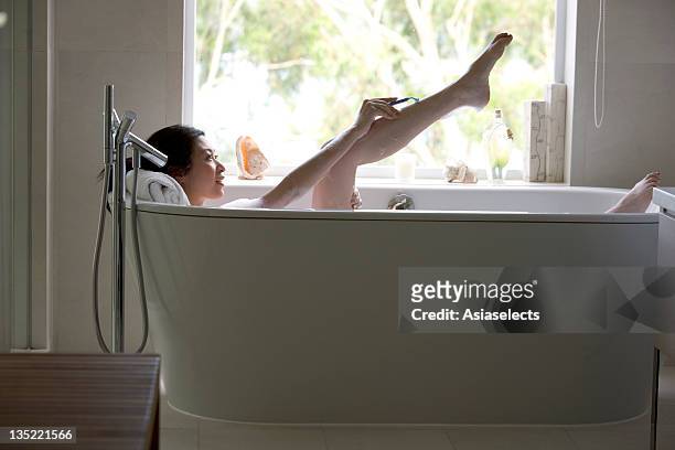 young woman shaving while taking a bath. - japanese women bath stock pictures, royalty-free photos & images