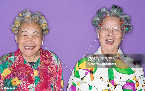 portrait of two senior women listening to music - hair curlers stock-fotos und bilder