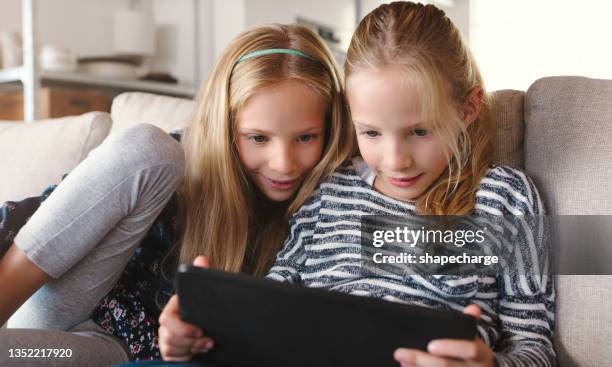 shot of two sisters relaxing together while using their digital tablet - digital twin bildbanksfoton och bilder