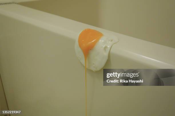 a fried egg caught on the edge of the bathtub - escapisme stockfoto's en -beelden