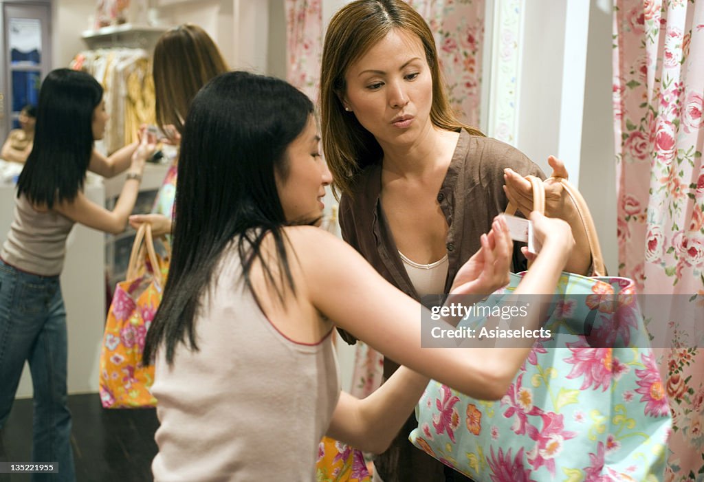 Close-up of two young women holding shopping bags in a clothing store
