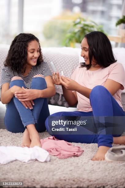 cropped shot of two teenage girls talking about menstruation at home - girl using tampon stockfoto's en -beelden