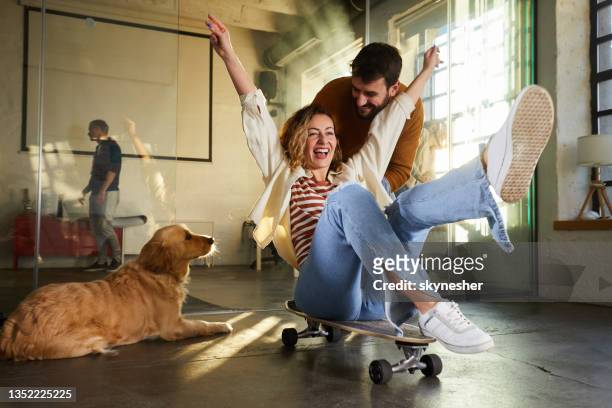 carefree couple having fun at casual office. - dog skateboard stock pictures, royalty-free photos & images