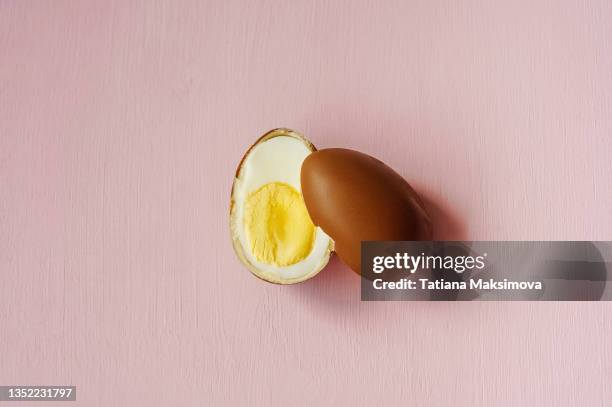 boiled chicken egg in a chocolate shell on pink background. - easter egg crack stock pictures, royalty-free photos & images