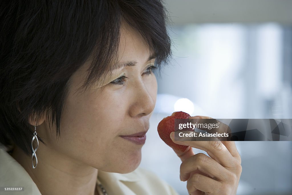 Close-up of a mid adult woman holding a strawberry close to her mouth