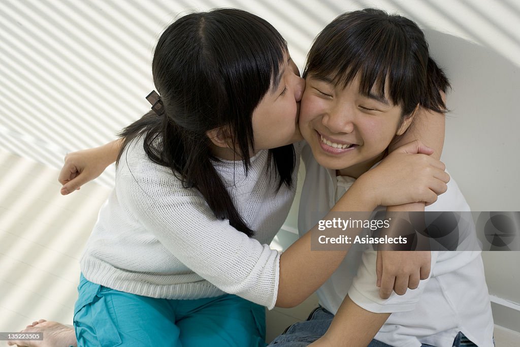 High angle view of a teenage girl kissing her sister