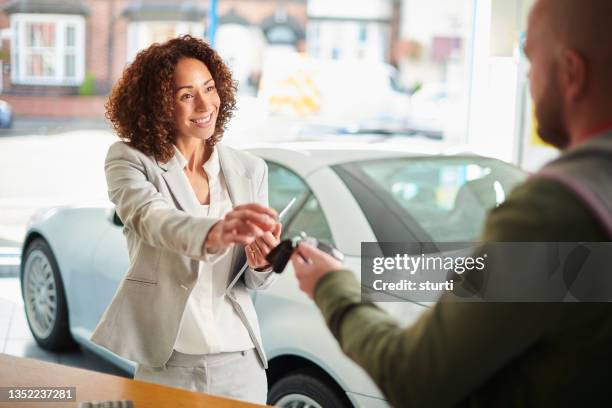 car sales person handing over keys - car rental stockfoto's en -beelden