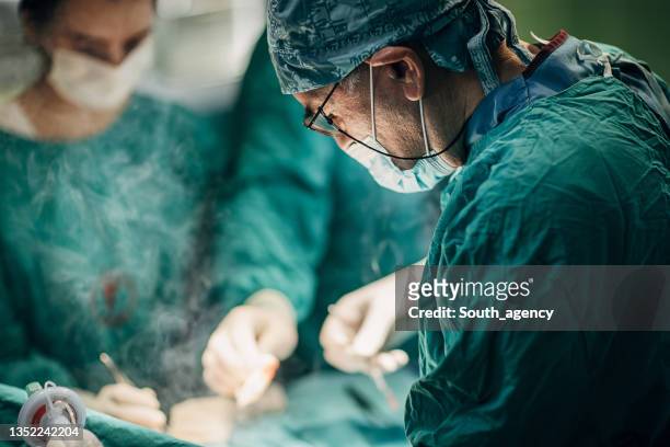 team von chirurgen, die operationen durchführen - operationskittel stock-fotos und bilder