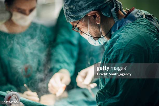 team of surgeons performing surgery - surgical equipment stockfoto's en -beelden