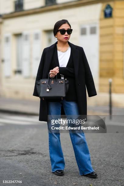 May Berthelot wears black sunglasses, gold earrings, a gold large chain and pearls necklace from Leo Sedim, a white t-shirt, a black wool blazer...