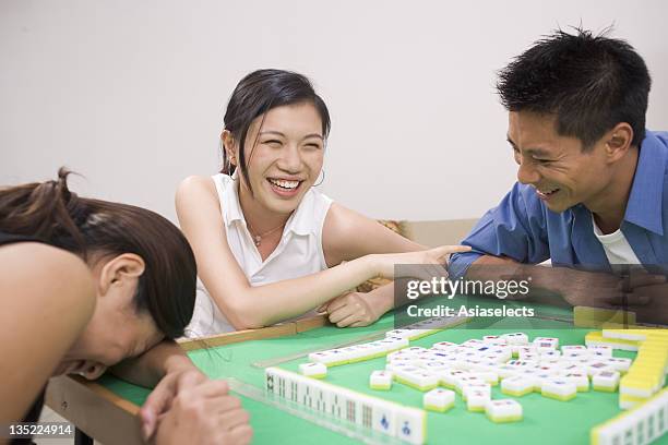 young man and two young women playing mahjong - woman smiling facing down stock pictures, royalty-free photos & images