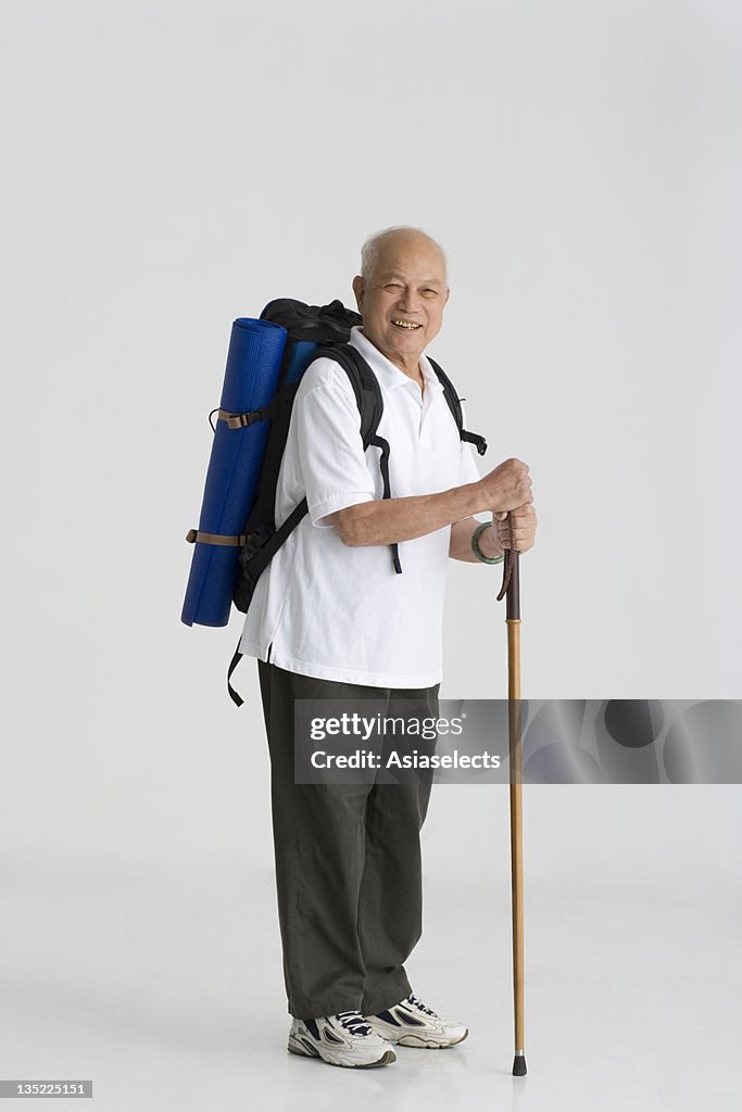 Portrait of a senior man holding a hiking pole and smiling