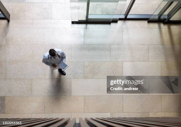 doctor walking through the entrance hall of a hospital - overhead view walking stock pictures, royalty-free photos & images