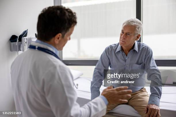 doctor talking to a patient in a consultaton at the office - mannelijk stockfoto's en -beelden
