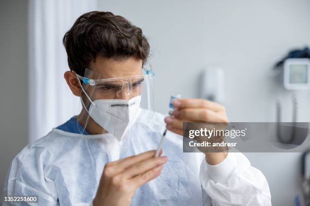 healthcare worker getting a covid-19 vaccine ready for application - biosecurity stock pictures, royalty-free photos & images