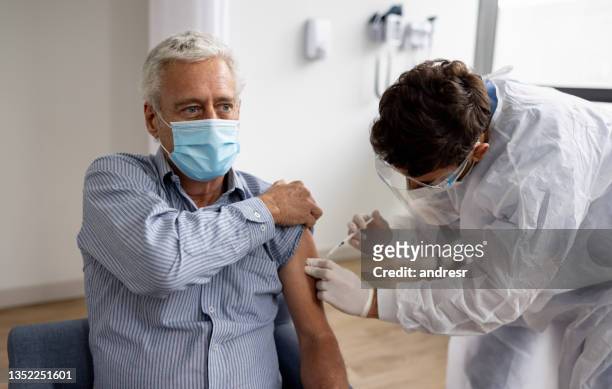 adult man getting a booster dose of the covid-19 vaccine at the hospital - covid 19 stock pictures, royalty-free photos & images