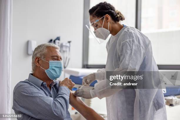 hombre adulto que recibe la vacuna contra el covid-19 en el hospital - n95 face mask fotografías e imágenes de stock