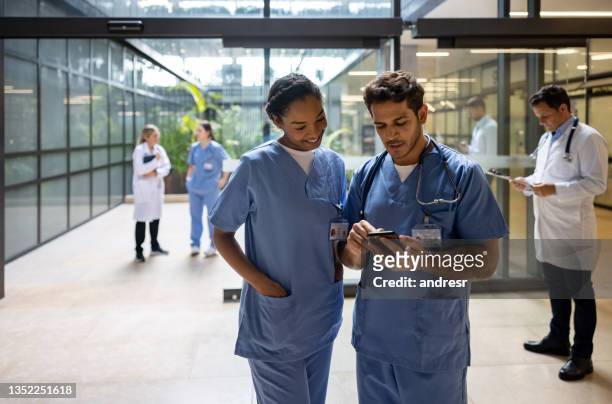doctor at the hospital showing something on his cell phone to a coworker - entrance stock pictures, royalty-free photos & images