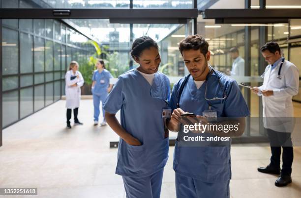 doctor at the hospital showing something on his cell phone to a coworker - entrance hall bildbanksfoton och bilder