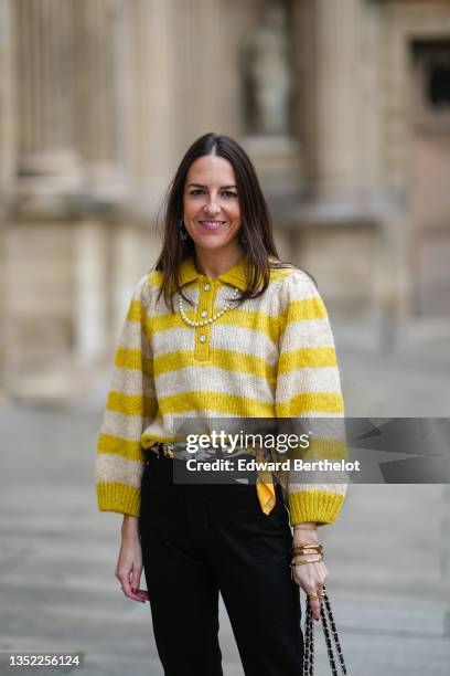 Alba Garavito Torre wears silver and pearls earrings, a yellow and white striped wool classic polo with the collar front placket opening to chest...