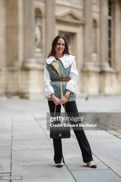 Alba Garavito Torre wears gold with pearls earrings, a pearls necklace, a black t-shirt, a white large collar and puffy sleeves with bow shirt form...