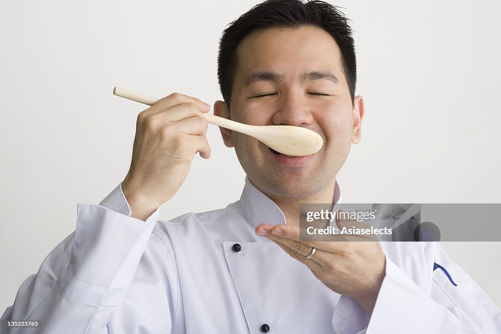 Close-up of a male chef tasting food and smiling