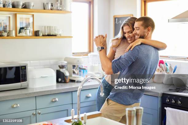 loving couple dancing together in kitchen at home - couple in kitchen stock pictures, royalty-free photos & images