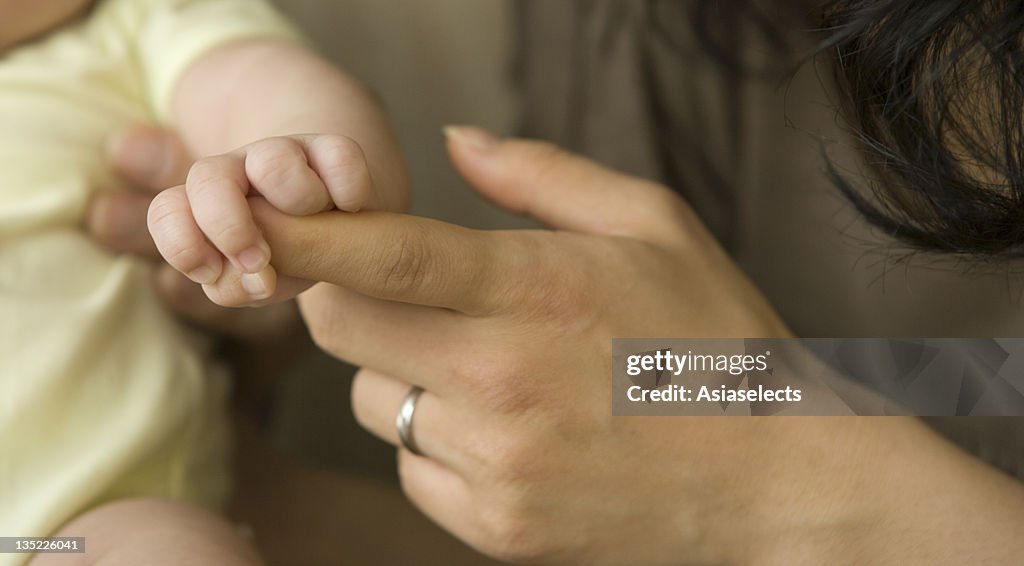 Baby girl holding her mother's hand