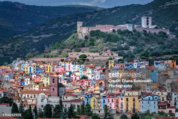colorful houses in the old village known as sa costa adorn the hillside below the medieval castle, castello di serravalle in the town of bosa - oristano fotografías e imágenes de stock