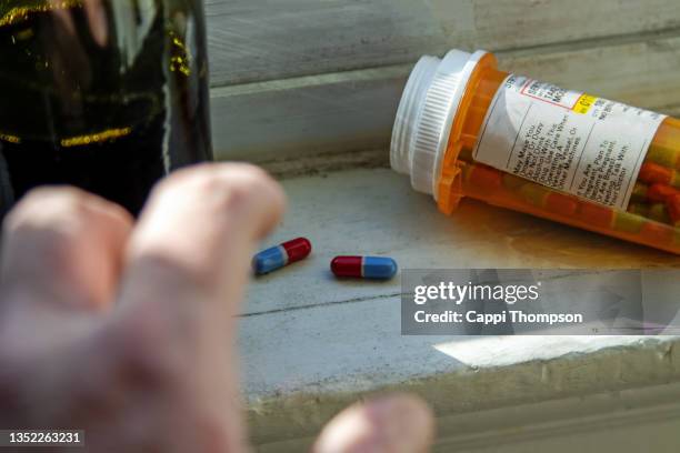 hand reaching for pills with wine bottle - opioid stock pictures, royalty-free photos & images