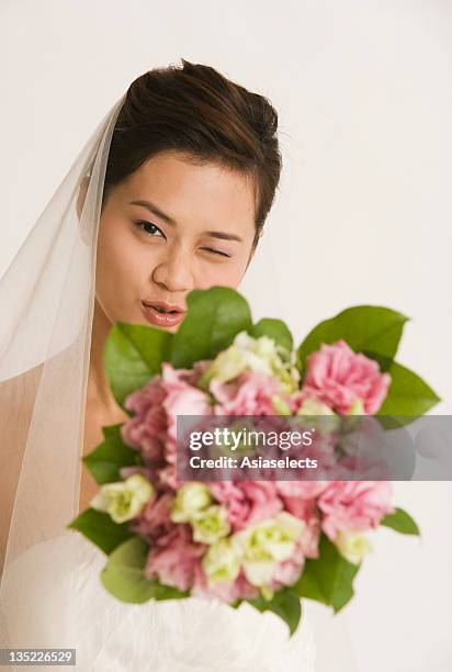 portrait of a bride showing a bouquet of flowers and winking - naughty bride stock pictures, royalty-free photos & images