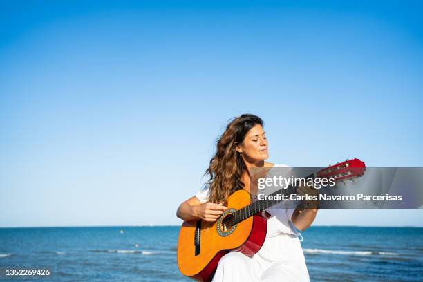 photo with copy space of a woman singuing and playing a guitar next to the sea - escritor de canções imagens e fotografias de stock
