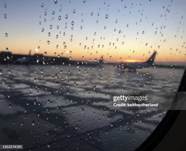 view through an aircraft window of planes on the tarmac in the rain, canada - airport rain ストックフォトと画像