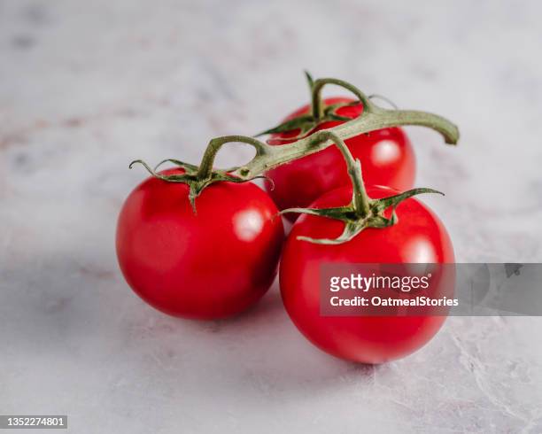 three vine tomatoes on a table - foodstyling stock-fotos und bilder
