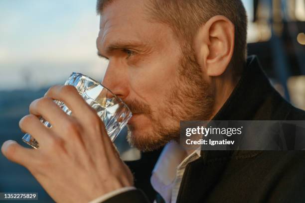 close -up of a profile of a sad thoughtful man,  drinking alcohol on a roof during the dawn - vodka bildbanksfoton och bilder