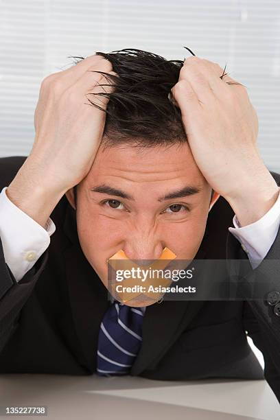 portrait of a businessman with duct tape on his lips and pulling his hair - man with tape on lips stock pictures, royalty-free photos & images