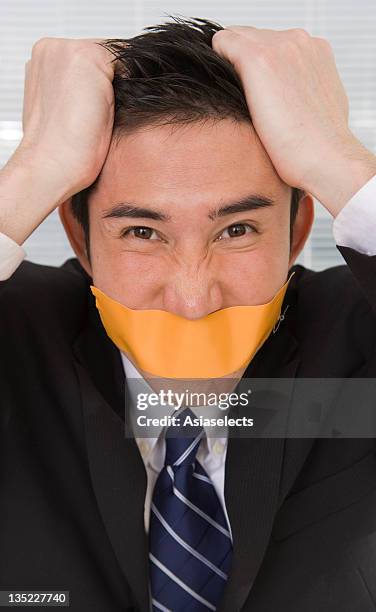 portrait of a businessman with duct tape on his lips and pulling his hair - man with tape on lips stock pictures, royalty-free photos & images