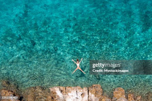 woman floating turquoise sea - 30-34 years stock pictures, royalty-free photos & images